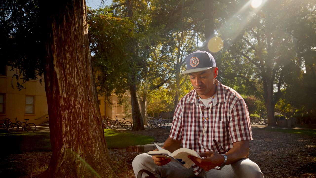 Student George Villa reads outdoors.